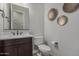 Bathroom featuring a dark wood vanity, white countertop, toilet, and decorative wall art at 14571 W Wethersfield Rd, Surprise, AZ 85379