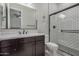 Bathroom with dark cabinets, white quartz countertops, large mirror and glass shower with white subway tile at 14571 W Wethersfield Rd, Surprise, AZ 85379