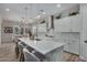 Bright kitchen features a large island with seating, white cabinets, stainless appliances, and stylish pendant lighting at 14571 W Wethersfield Rd, Surprise, AZ 85379
