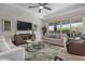 Bright living room with a ceiling fan, large TV, comfortable seating, and sliding glass doors to the backyard at 14571 W Wethersfield Rd, Surprise, AZ 85379