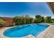 Backyard swimming pool with a brick wall and lush green landscaping at 14571 W Wethersfield Rd, Surprise, AZ 85379