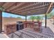 Outdoor kitchen under a pergola with a built-in grill and bar area, overlooking the pool at 1761 N Hester Trl, Casa Grande, AZ 85122