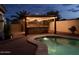 Nighttime view of backyard pool with a pergola and outdoor kitchen illuminated with string lights at 1761 N Hester Trl, Casa Grande, AZ 85122