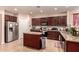 Spacious kitchen with stainless steel refrigerator, large island, and dark wood cabinets at 17825 W Lincoln St, Goodyear, AZ 85338