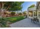 Relaxing backyard view of a lush lawn, mature tree, brick-paved patio, and comfortable seating area at 2045 E San Carlos Pl, Chandler, AZ 85249