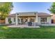 Large backyard featuring a covered patio with grill and seating, a lush lawn, and manicured landscaping, perfect for entertaining at 2045 E San Carlos Pl, Chandler, AZ 85249