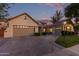 Lovely home featuring a three-car garage, a cozy front patio, and a well-maintained lawn at dusk at 2045 E San Carlos Pl, Chandler, AZ 85249