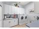 Laundry room with white cabinets, sink, washer, dryer, and neutral colored tile flooring at 2045 E San Carlos Pl, Chandler, AZ 85249