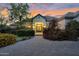 Stunning home exterior featuring a brick driveway, lush landscaping, and a warm, inviting entrance at dusk at 20644 E Sunrise Ct, Queen Creek, AZ 85142