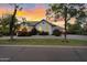 Beautiful house exterior showcasing mature trees, a green lawn, fresh landscaping, and well lit facade at dusk at 20644 E Sunrise Ct, Queen Creek, AZ 85142