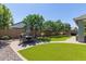 This backyard features a manicured lawn, mature trees, and an outdoor dining table with seating for six at 23179 S 225Th Pl, Queen Creek, AZ 85142