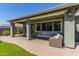 This covered patio features brick flooring, columns, recessed lights, a ceiling fan, and outdoor seating at 23179 S 225Th Pl, Queen Creek, AZ 85142