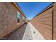 Narrow side yard featuring a stone path between the house and a stucco wall under a bright blue sky at 2368 E Bellerive Dr, Gilbert, AZ 85298