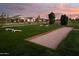 Bocce ball court surrounded by green grass and landscaping with beautiful luxury homes in the background at 24000 S 218Th Pl, Queen Creek, AZ 85142