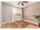Bedroom with hardwood floors, ceiling fan, wood accent wall, and window with natural light at 26521 N Babbling Brook Dr, Phoenix, AZ 85083