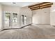 A large living room with carpeting features beamed ceilings, and access to the backyard at 27347 N Gary Rd, San Tan Valley, AZ 85144
