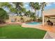 Lush backyard with artificial grass, palm trees, and a sparkling pool, creating a relaxing outdoor retreat at 4043 N Ranier --, Mesa, AZ 85215