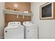 Well-lit laundry room with new washer and dryer, storage shelves, and decorated with trendy artwork at 5806 E Axle Ln, San Tan Valley, AZ 85140