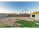 Backyard with a mix of dirt and grass, surrounded by a wooden fence and palm trees on the horizon at 6960 W Berkeley Rd, Phoenix, AZ 85035