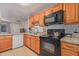 Galley kitchen features granite countertops, wood cabinets, and black appliances at 6960 W Berkeley Rd, Phoenix, AZ 85035