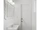 All-white bathroom featuring a square mirror, sink, updated lighting, and a door to the backyard at 710 E Hayward Ave, Phoenix, AZ 85020