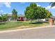 Charming single-story home with lush green lawn, mature trees, and inviting red front door at 710 E Hayward Ave, Phoenix, AZ 85020