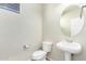 Cozy powder room featuring a pedestal sink, toilet, and round mirror for added convenience at 9148 W Meadow Dr, Peoria, AZ 85382