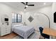 Bright bedroom with a large window, ceiling fan, hardwood floors, and a cozy sitting area with modern decor at 1013 W Ardmore Rd, Phoenix, AZ 85041