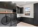Modern laundry room with sleek, black cabinets, new washer and dryer, and a window with garden view at 1013 W Ardmore Rd, Phoenix, AZ 85041