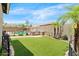 Lush backyard featuring artificial turf, outdoor kitchen, sparkling pool and beautiful desert landscaping at 11958 W Villa Chula Ln, Sun City, AZ 85373