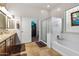 Bathroom featuring double vanity, soaking tub with glass door and a stained glass window at 11958 W Villa Chula Ln, Sun City, AZ 85373