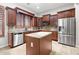 Kitchen featuring stainless steel appliances, a center island, tile backsplash, and wooden cabinets with decorative trim at 11958 W Villa Chula Ln, Sun City, AZ 85373