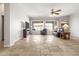An open living room with travertine floors, ceiling fan, and large windows allowing for abundant natural light at 11958 W Villa Chula Ln, Sun City, AZ 85373