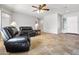 Spacious living room featuring travertine tile floors, neutral walls, ceiling fan, and a welcoming ambiance at 11958 W Villa Chula Ln, Sun City, AZ 85373