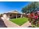Backyard featuring a covered patio, a small section of grass, trees, and rock landscaping at 13439 W Desert Ln, Surprise, AZ 85374