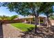 Backyard featuring a covered patio, a small section of grass, trees, and rock landscaping at 13439 W Desert Ln, Surprise, AZ 85374