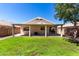 Wide shot of the backyard with a grassy area, covered patio, and rock landscaping at 13439 W Desert Ln, Surprise, AZ 85374