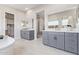 A stylish main bathroom featuring dual sinks, white counters, and access to the walk-in closet at 14116 W Honeysuckle Dr, Surprise, AZ 85387