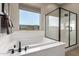 Stylish bathroom with sleek soaking tub, walk-in shower, and large window with natural light at 14124 W Honeysuckle Dr, Surprise, AZ 85387