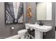 Chic powder room featuring a pedestal sink, modern fixtures, and decorative wall art at 14124 W Honeysuckle Dr, Surprise, AZ 85387