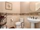 Charming powder room with a pedestal sink, decorative mirror, and neutral tile at 1526 E Hazel Dr, Phoenix, AZ 85042