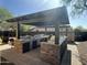 This outdoor kitchen features a built-in grill and stainless steel drawers and is located underneath a pergola at 1526 E Hazel Dr, Phoenix, AZ 85042