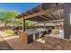Outdoor kitchen boasts a grill, countertop space, and shaded pergola, perfect for al fresco dining at 1526 E Hazel Dr, Phoenix, AZ 85042