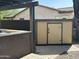 A tan storage shed with black hardware sits on a paver pad and is used for storing yard tools and equipment at 1526 E Hazel Dr, Phoenix, AZ 85042