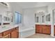 Bright bathroom with dual sinks, bathtub, large mirrors and wood cabinets at 21759 E Estrella Rd, Queen Creek, AZ 85142