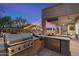 A covered outdoor kitchen features a built-in grill, bar area, refrigerator, and backyard views at 22233 N 54Th Way, Phoenix, AZ 85054