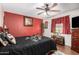 Bedroom featuring ceiling fan, red accent wall, and wooden floors at 2419 E Billings St, Mesa, AZ 85213