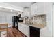 Kitchen showcasing white cabinets, wooden floors, black appliances, and tiled backsplash at 2419 E Billings St, Mesa, AZ 85213