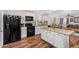 Kitchen featuring wooden floors, black appliances, white cabinets, and a center island with sink at 2419 E Billings St, Mesa, AZ 85213