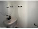 Neat powder room featuring a pedestal sink, a round mirror and black hardware at 32661 N Newby Dr, San Tan Valley, AZ 85143